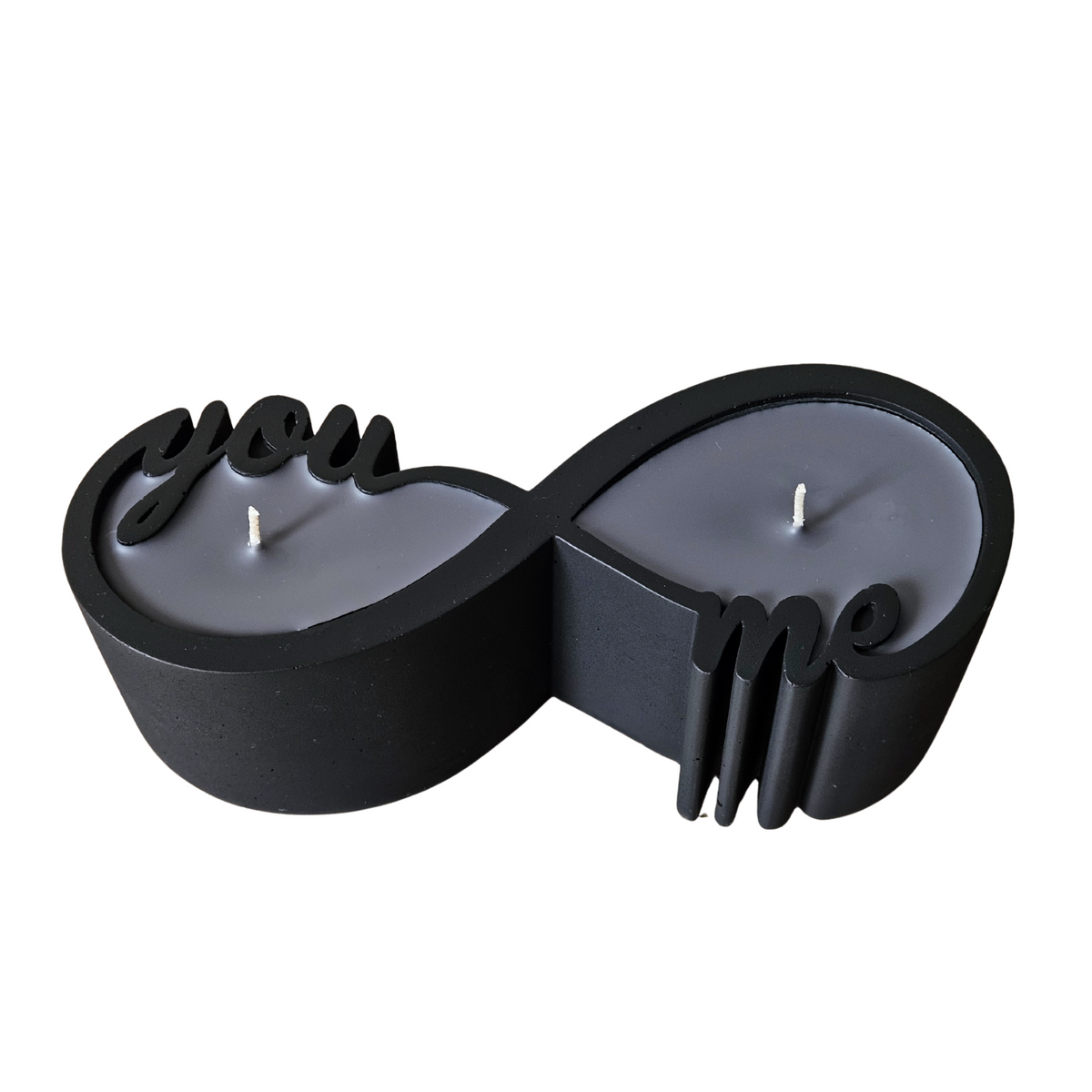 Eine elegante, matte schwarze Infinity-Gipskerze mit dunkelgrauem Sheawachs auf weissem Hintergrund.
