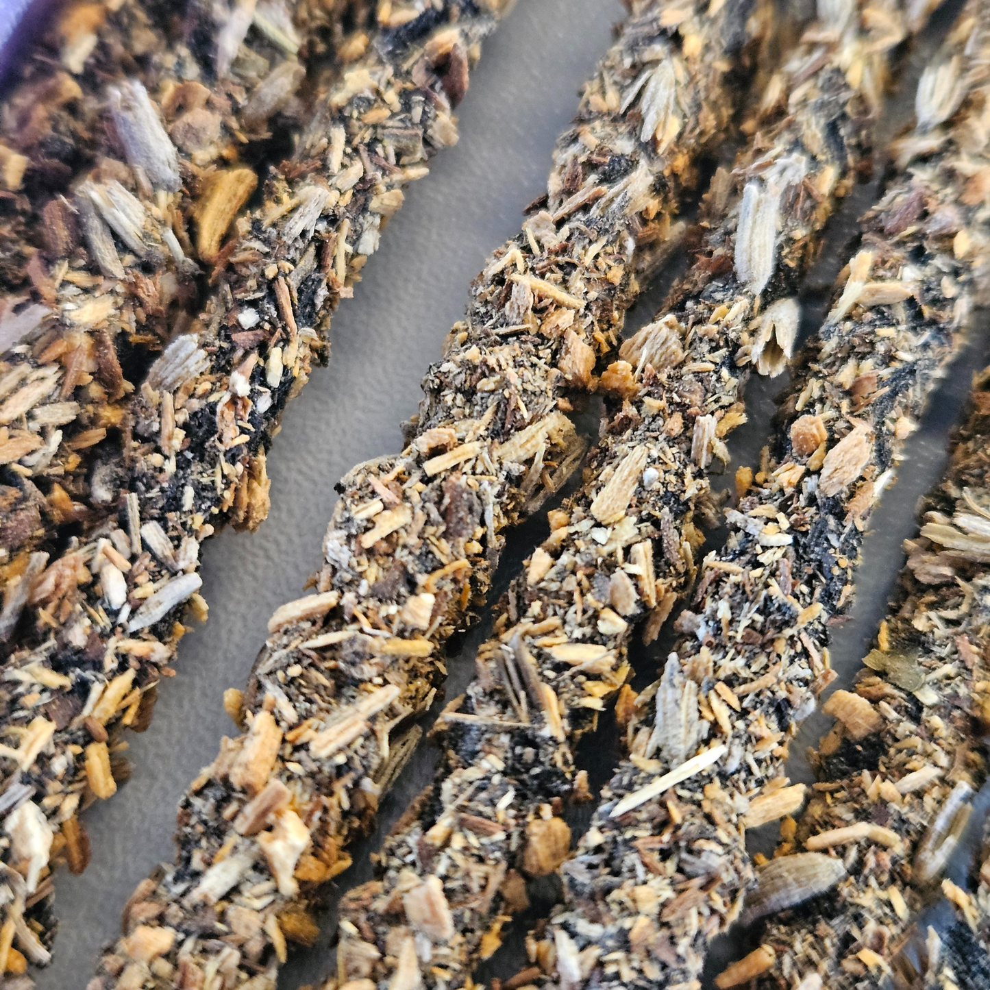 Detailaufnahme der Sagrada Madre Palo Santo Räucherstäbchen mit Lavendel – grobe Struktur aus Kräutern und Holzstücken.