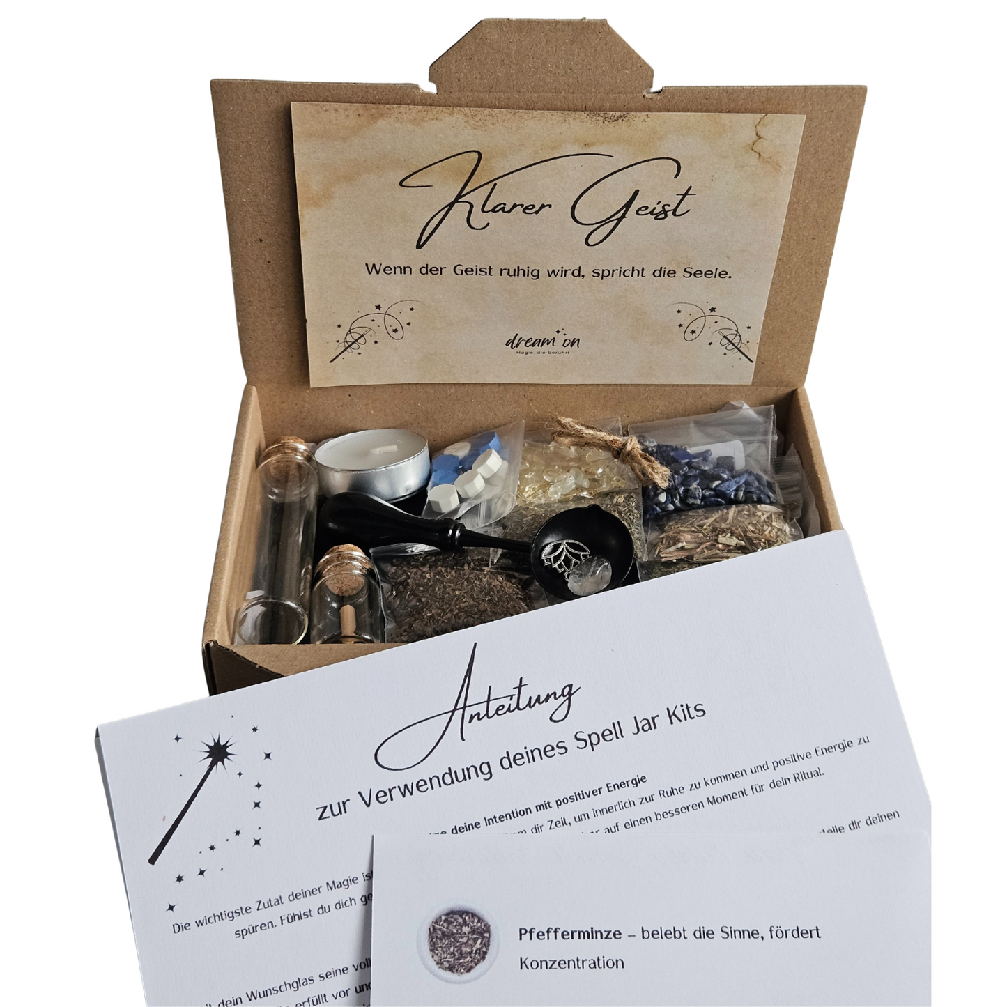 Geöffnete Geschenkbox des DIY-Kreativsets Klarer Geist von DreamOn, gefüllt mit Naturmaterialien und Zubehör. Im Vordergrund liegt eine gedruckte Anleitung zur Verwendung des Sets mit Beschreibungen zu Pfefferminze, Bergkristall und Lapislazuli.