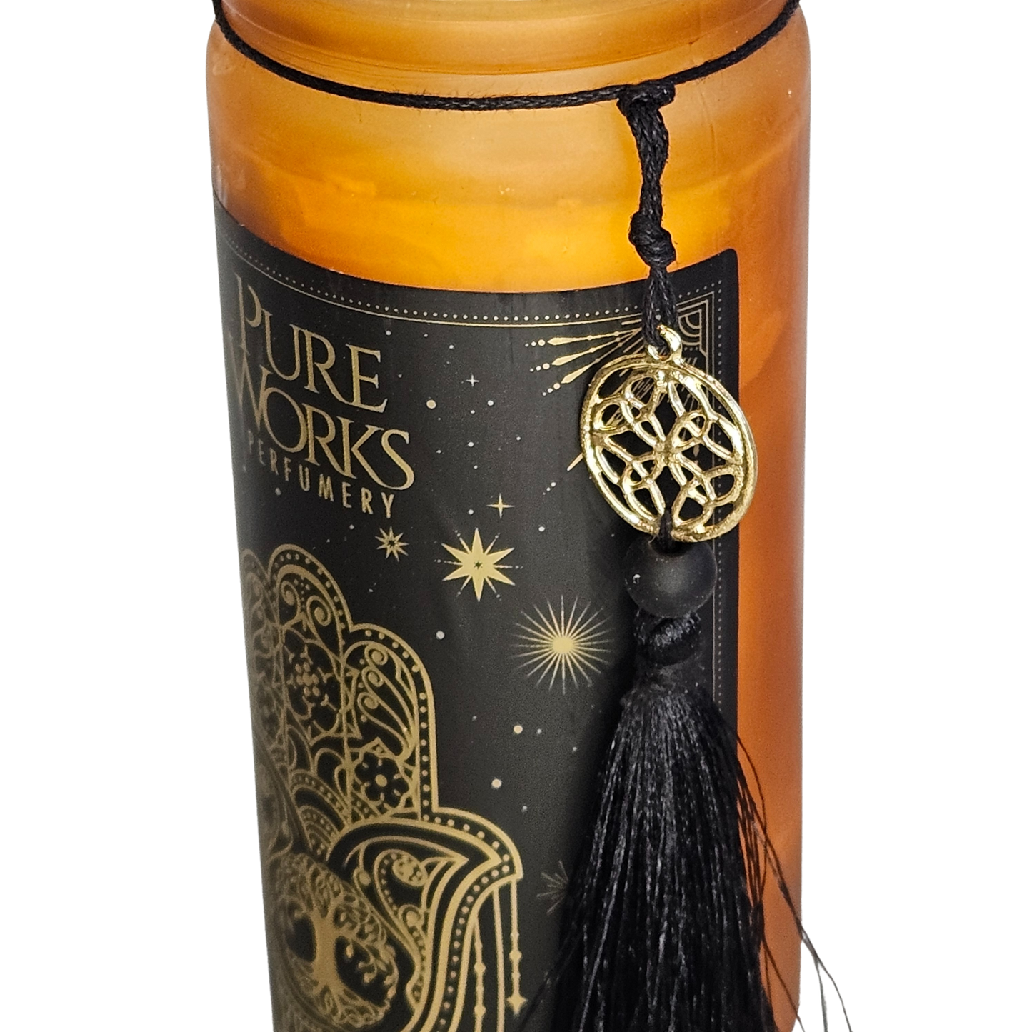 Detailansicht der bernsteinfarbenen Glas-Duftkerze mit der goldenen Verzierung, dem PureWorks-Logo und der befestigten schwarzen Stoffquaste.