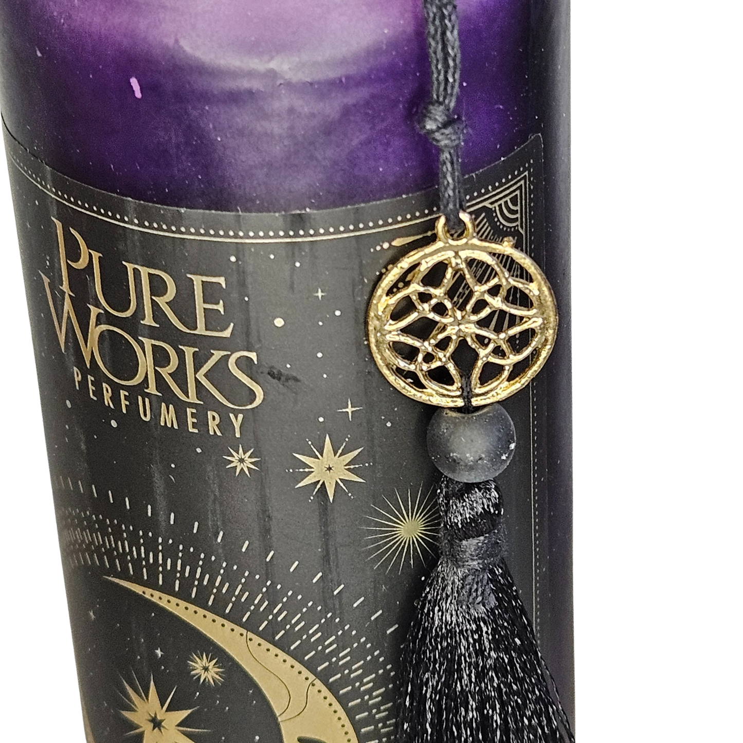 Detailansicht der dunkelblauen Glas-Duftkerze mit der goldenen Verzierung, dem PureWorks-Logo und der befestigten schwarzen Stoffquaste.