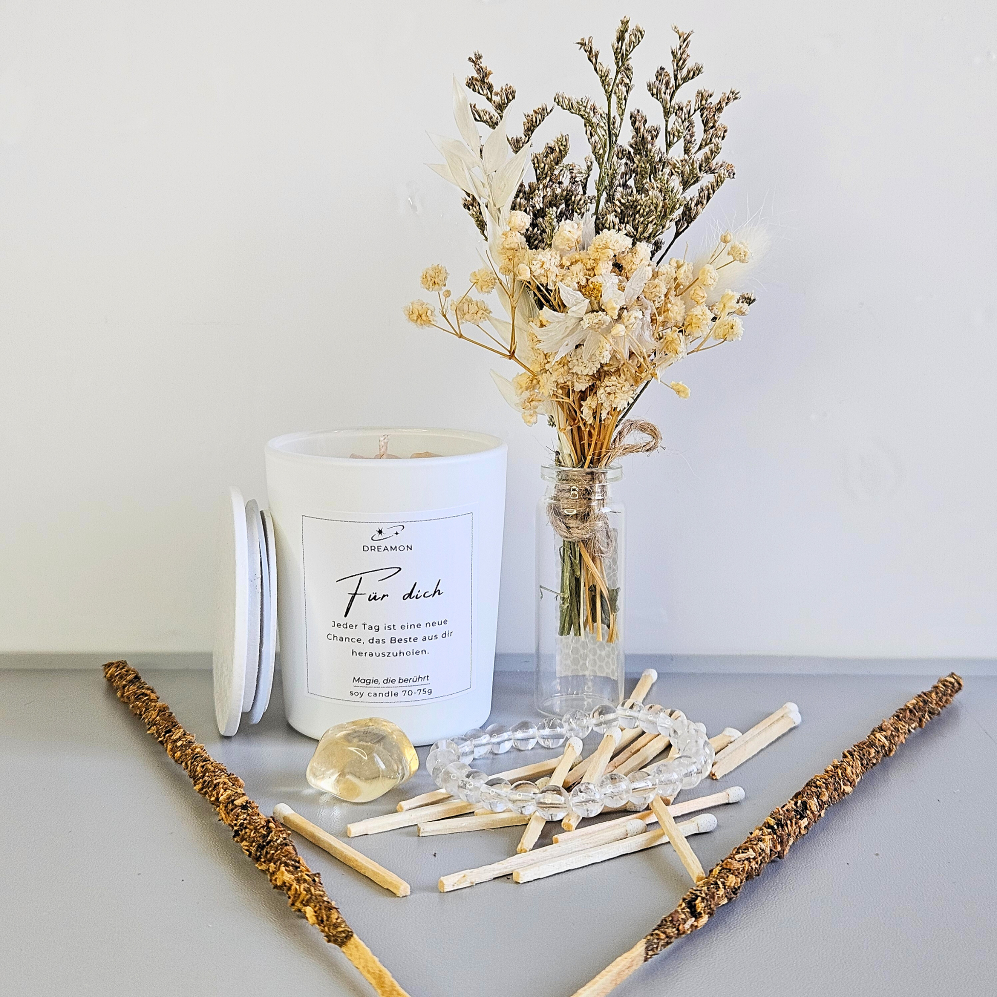 Magisches Geschenkset „Für dich“ arrangiert – weiße Kerze mit Edelsteinen, Mondstein-Armband, Mondstein, Trockenblumenstrauß, Streichhölzer und zwei Räucherstäbchen.