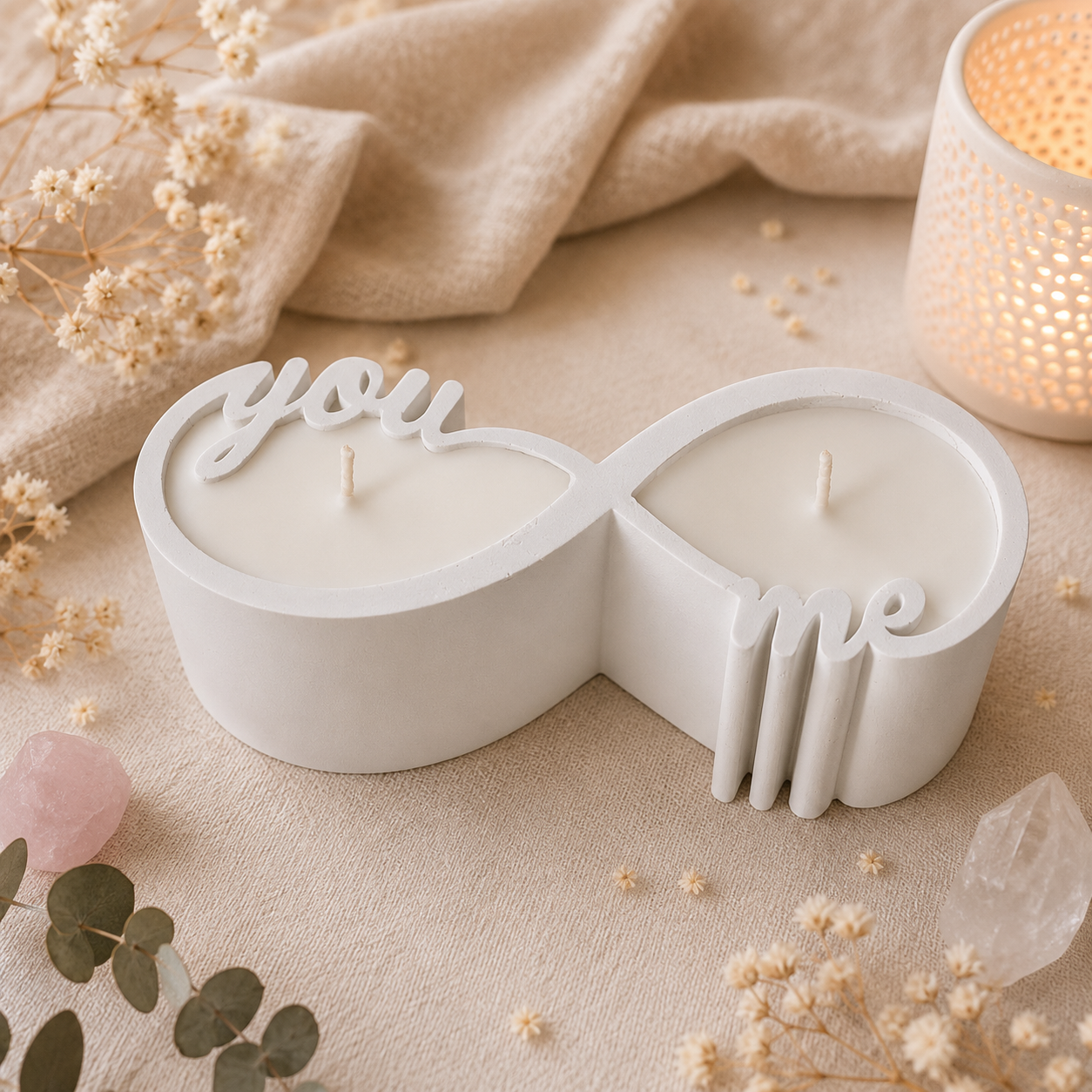 Stimmungsvolle Produktfotografie der weissen Unendlichkeits-Kerze aus Gips mit hellem Naturwachs, umgeben von Trockenblumen und Heilsteinen.