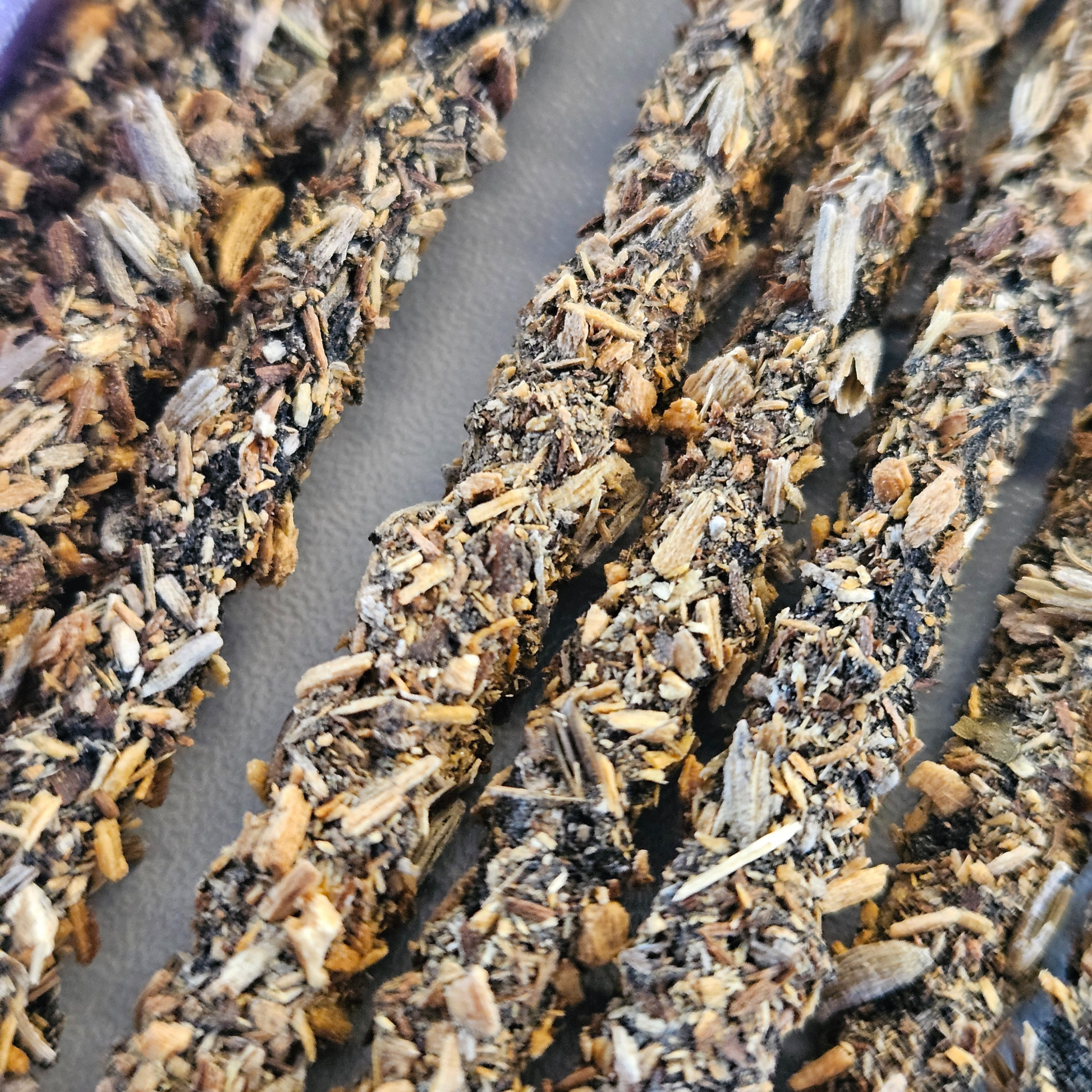 Detailaufnahme der Sagrada Madre Palo Santo Räucherstäbchen mit Lavendel – grobe Struktur aus Kräutern und Holzstücken.