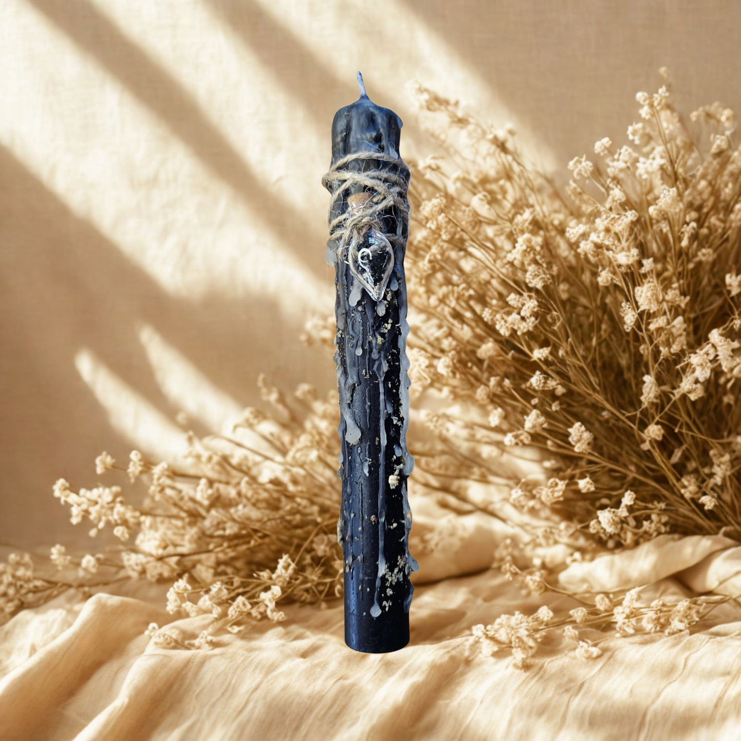 Schwarze Schutz- und Transformationskerze im natürlichen Setting – handgegossen und veredelt mit Eichenrinde, Salbei, Patchouli und Zedernholzöl.