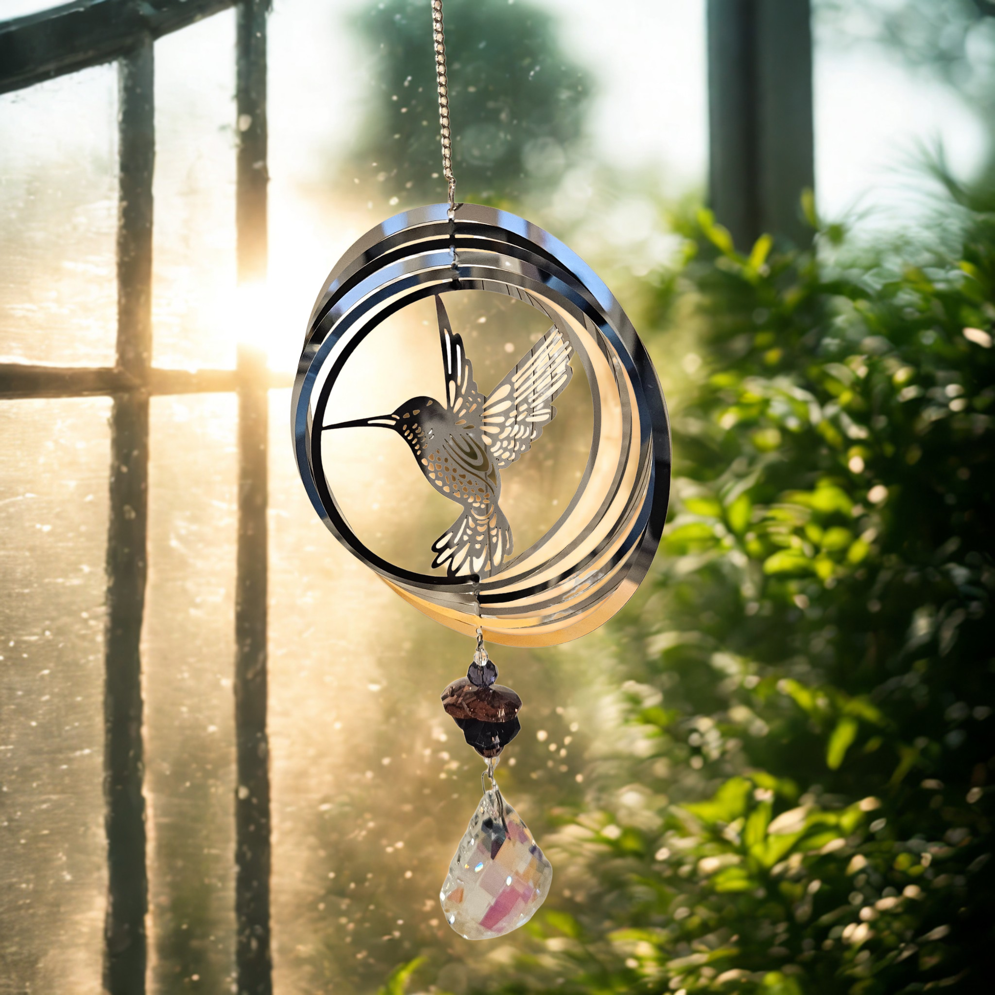 Metall-Suncatcher Windspiel mit Kolibri und Kristalltropfen, hängend im Sonnenlicht vor einem Fenster.