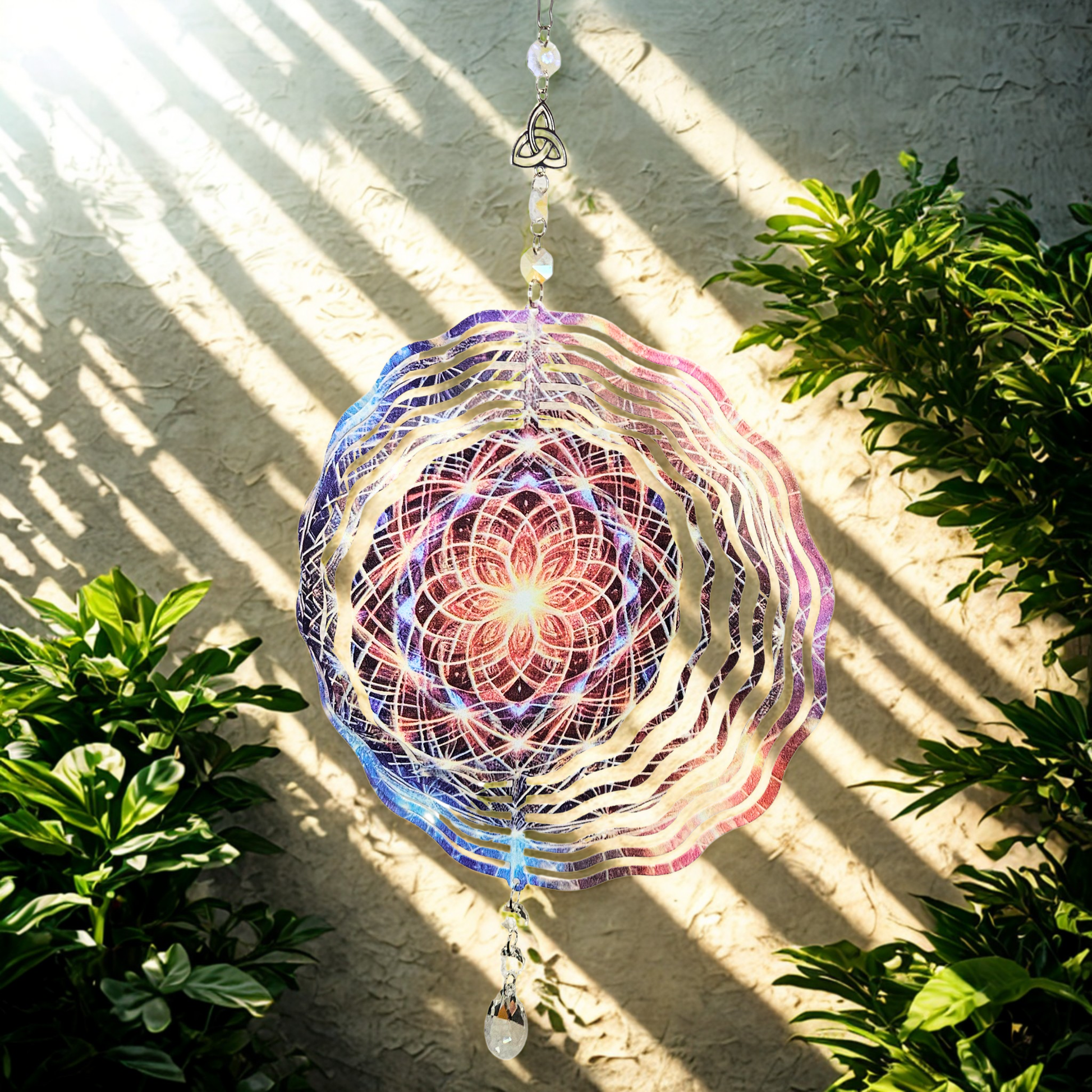 Stimmungsbild Windspinner Blume des Lebens aus Metall mit kosmischem Lichtmotiv und Kristalltropfen, vollständige Ansicht.