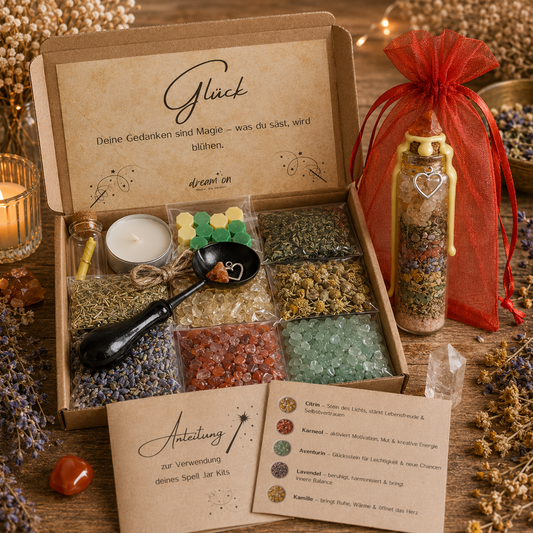 Geöffnete Geschenkbox des DIY-Kreativsets Glück von DreamOn mit Citrin, Karneol, Aventurin und Kräutern. Rechts steht das fertig geschichtete Wunschglas mit gelbem Wachssiegel vor einem leuchtend roten Organzasäckchen, im Vordergrund liegt die gedruckte Anleitung.