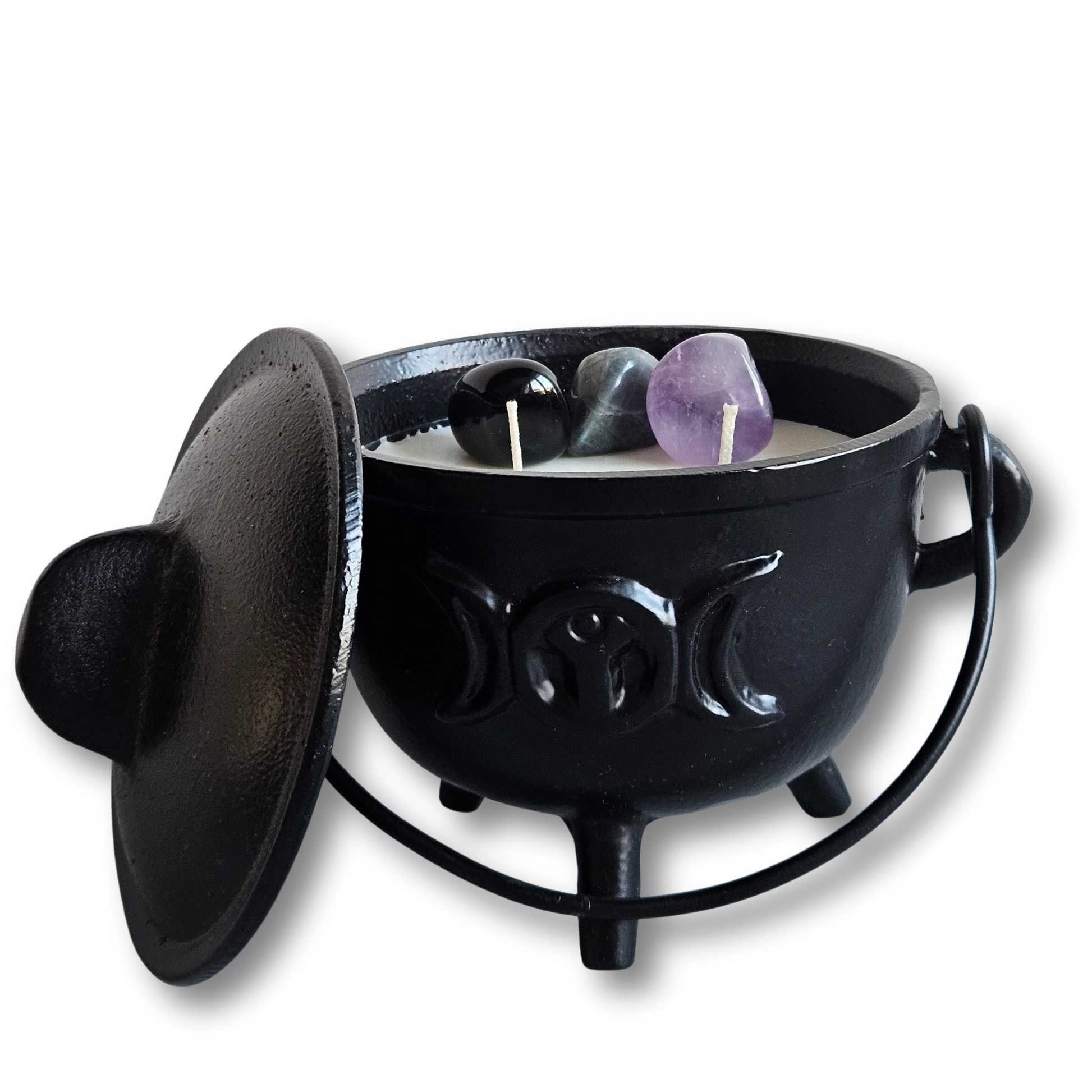 Große gusseiserne Duftkerze mit geöffnetem Deckel und den Edelsteinen Obsidian, Labradorit und Amethyst auf weißem Naturwachs.