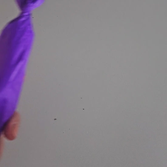 Video wie die Ritualkerze in Aubergine mit Glasfläschchen ausgepackt wird.